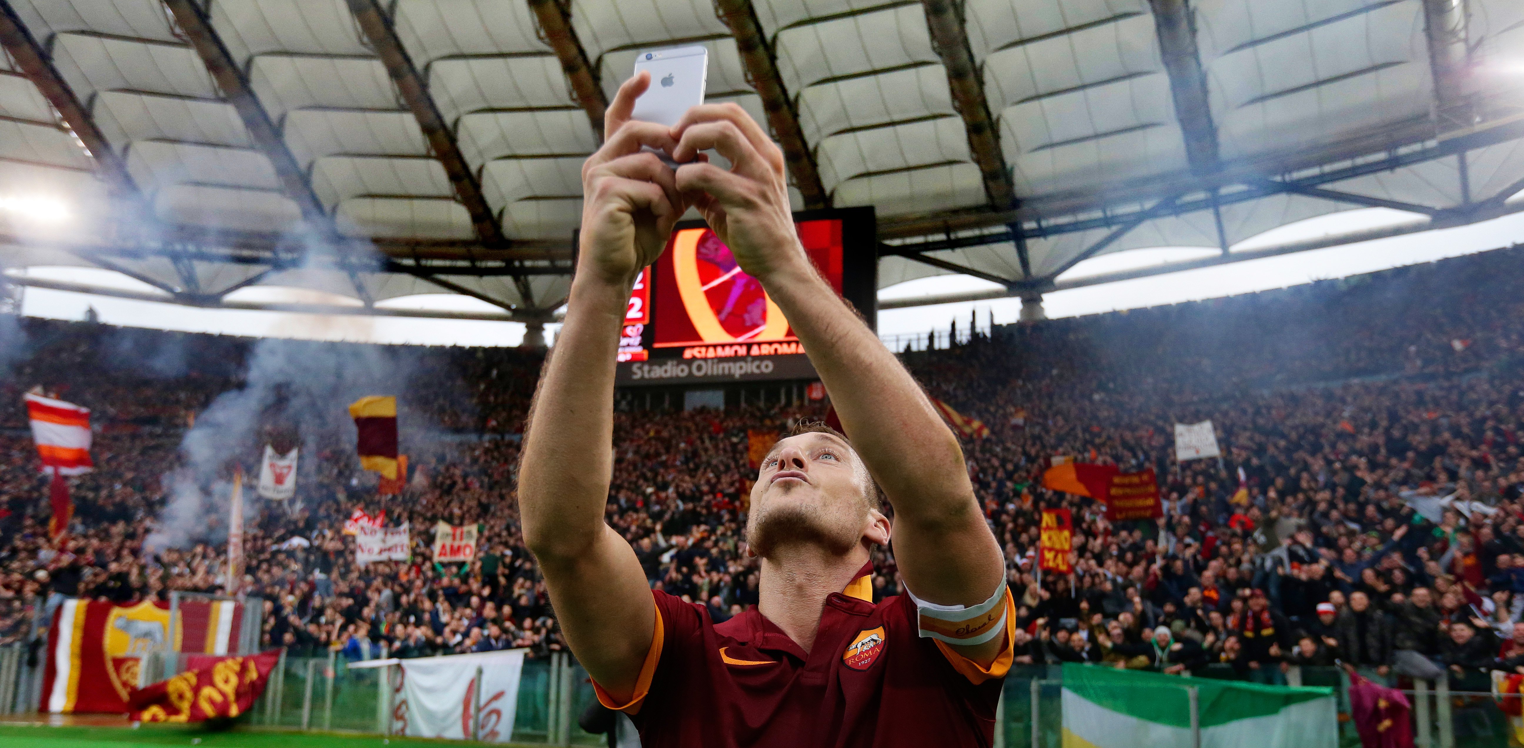 Francesco Totti als speler van AS Roma maakt een selfie met supporters na de wedstrijd, waarbij de smartphone symbool staat voor hoe fans en voetbal altijd verbonden blijven.
