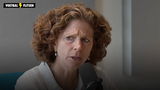Barbara Barend tijdens podcast-opname, met op de achtergrond het logo van Sportnieuws.nl in Oranje. Close-up portret waarbij haar kritische blik de ernst van haar boodschap over vrouwenvoetbal onderstreept.