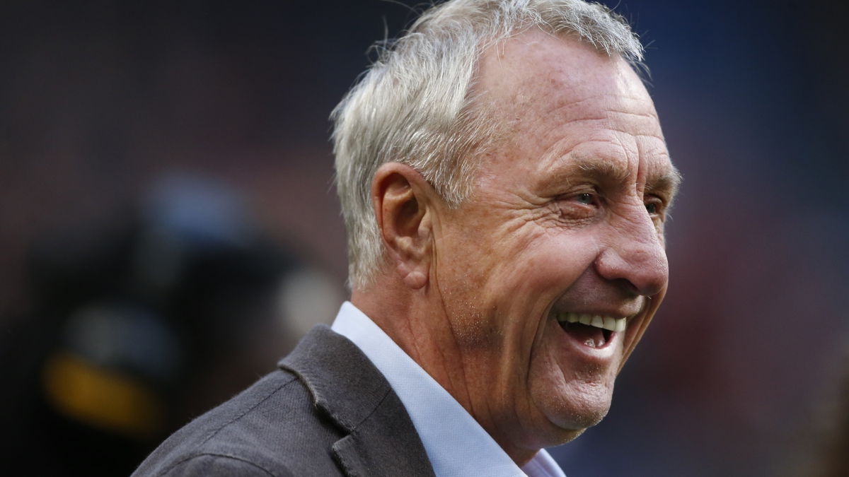 Johan Cruijff tijdens een ontspannen moment langs het veld, symbool voor zijn blijvende invloed op het voetbal.