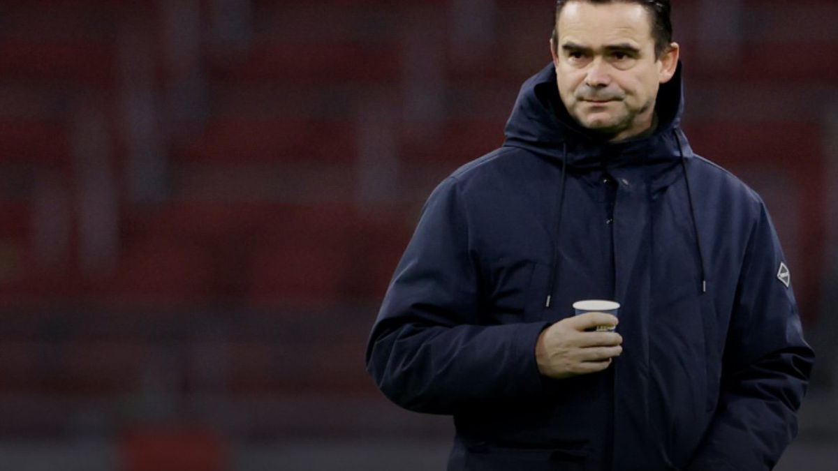 alex kroes vertrekt bij ajax, marc overmars wordt genoemd als opvolger. maar zijn teurgkeer zou op te veel verzet stuiten binnen ajax. overmars op de foto in de arena met een kop koffie in de hand op het veld